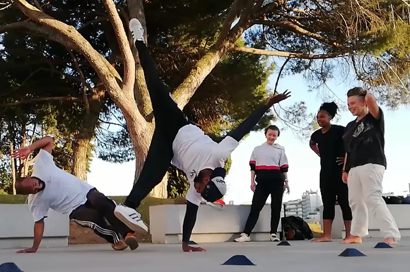 Roda de capoeira ao ar livre debaixo de um pinheiro, em Lisboa.