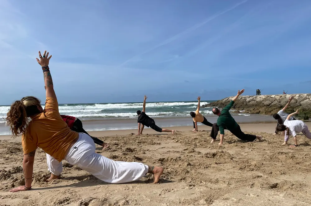 Treino de capoeira na praia, com berimbaus e o mar ao fundo.